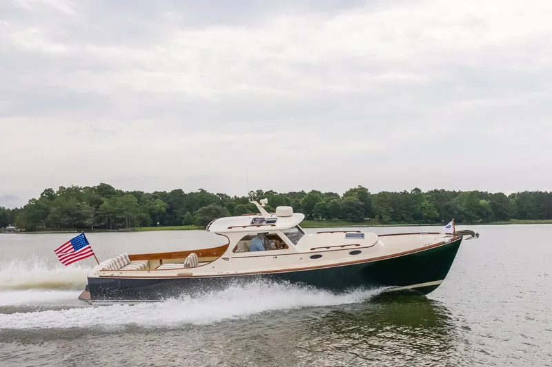 Slide: The Image of Hinckley Picnic Boat 36 Classic 2000 cruising on a serene lake with American flag. - 13