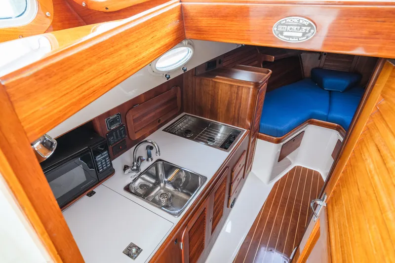 Slide: The Image of Hinckley Picnic Boat 36 Classic 2000 interior with wood finish, kitchenette, and blue seating. - 47