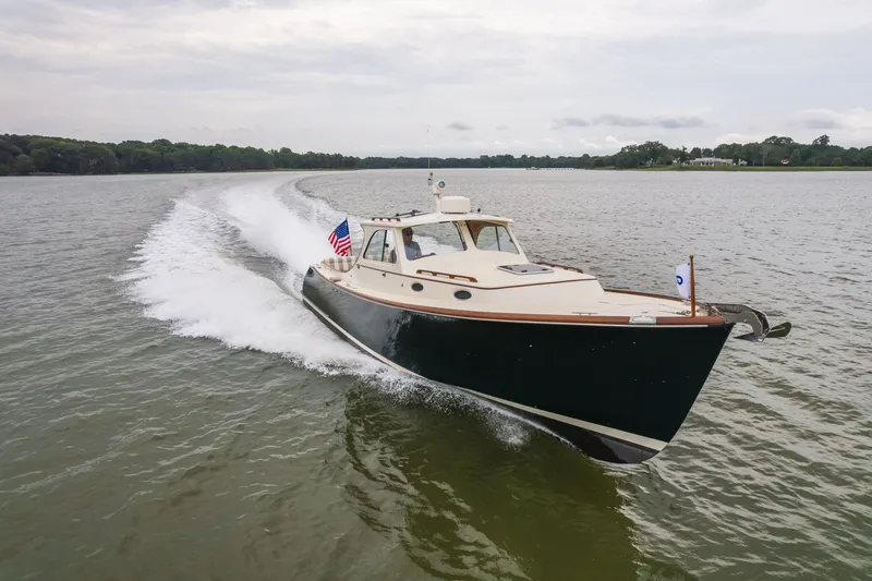 Slide: The Image of Hinckley Picnic Boat 36 Classic 2000 cruising on a serene lake with American flag. - 17