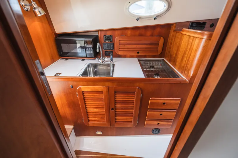 Slide: The Image of Hinckley Picnic Boat 36 Classic 2000 galley with wood cabinetry, sink, and microwave. - 60