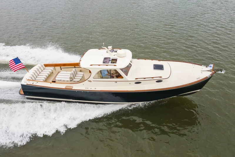 Slide: The Image of 2000 Hinckley Picnic Boat 36 Classic cruising on water, displaying elegant design and American flag. - 12
