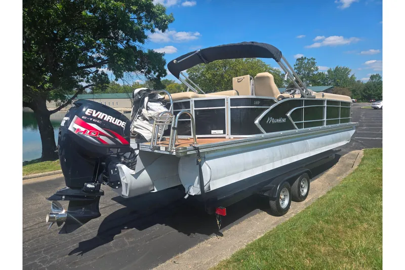Slide: The Image of 2012 Manitou 25 Legacy pontoon boat with Evinrude E-TEC engine on a trailer. - 1
