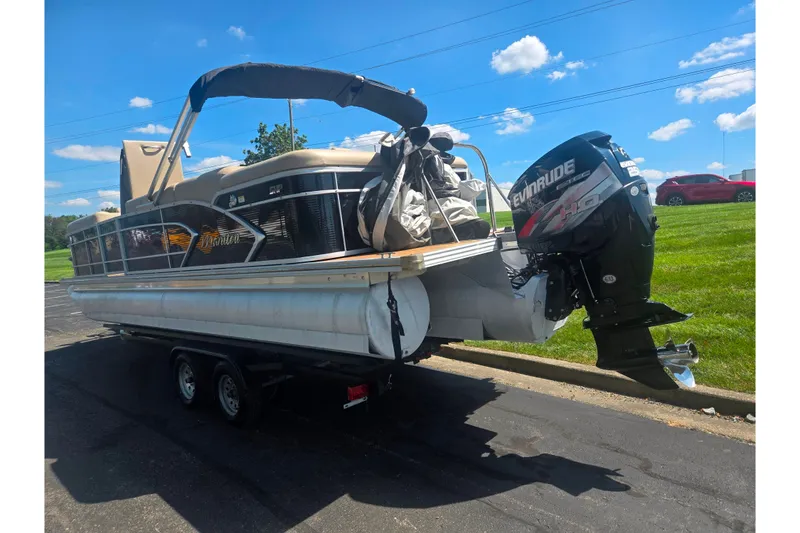 Slide: The Image of 2012 Manitou 25 Legacy pontoon boat with Evinrude engine on trailer, parked outdoors. - 3