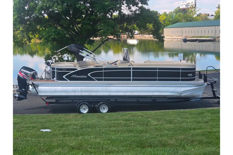 The Image of 2012 Manitou 25 Legacy pontoon boat on trailer by a scenic lake. - 0