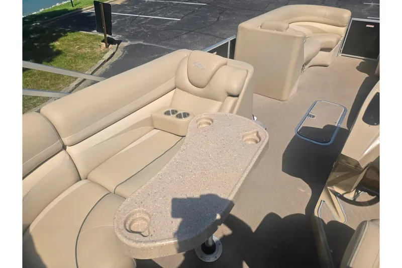 Slide: The Image of Interior of a 2012 Manitou 25 Legacy pontoon boat with beige seating and table. - 22