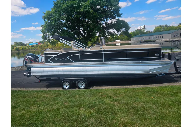 Slide: The Image of 2012 Manitou 25 Legacy pontoon boat on trailer by a lake, under a clear sky. - 9