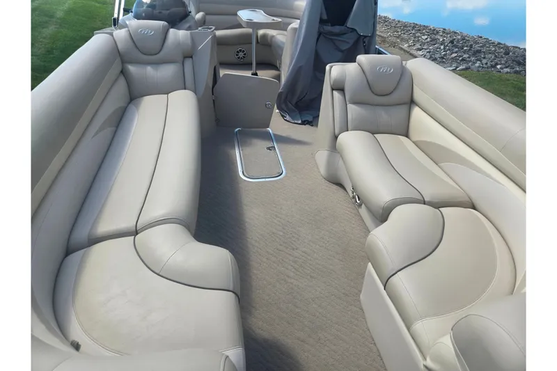 Slide: The Image of 2012 Manitou 25 Legacy boat interior with beige seating and carpet flooring. - 10