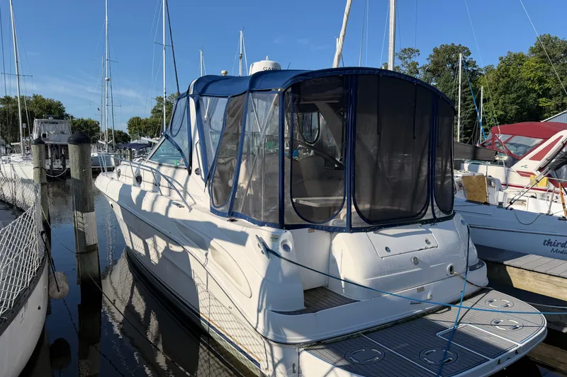 The Image of 2002 Sea Ray 340 Sundancer docked at marina, featuring blue canopy and sleek design. - 1