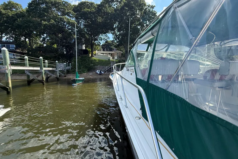 Slide: The Image of 2000 Mainship Pilot 30 docked near a wooden pier, surrounded by trees and calm water. - 9