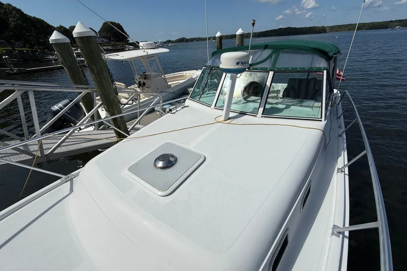 Slide: The Image of 2000 Mainship Pilot 30 docked at marina, featuring green canopy and sleek design. - 3