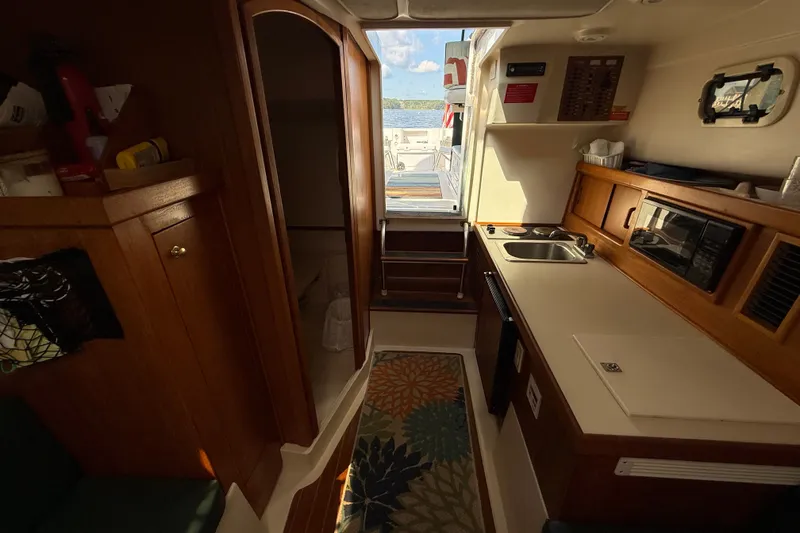 Slide: The Image of Interior of 2000 Mainship Pilot 30 boat with kitchenette and wooden cabinetry. - 22