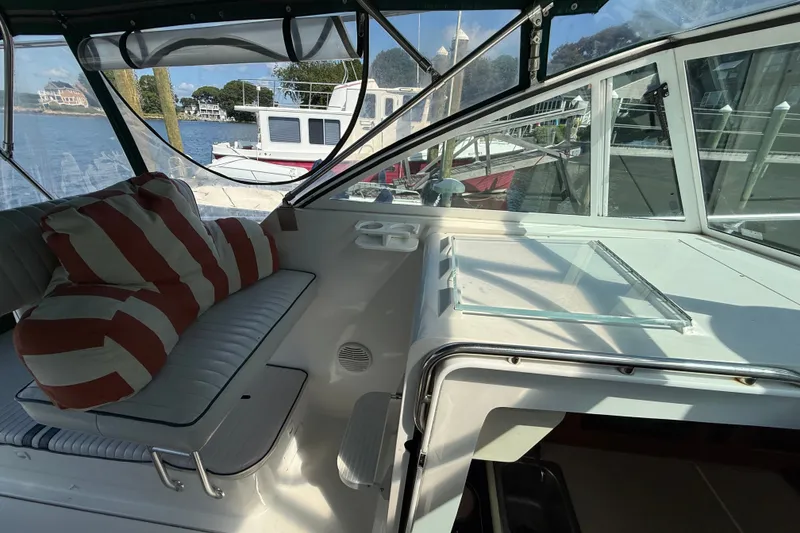Slide: The Image of Interior view of a 2000 Mainship Pilot 30 boat with striped cushions and marina backdrop. - 16