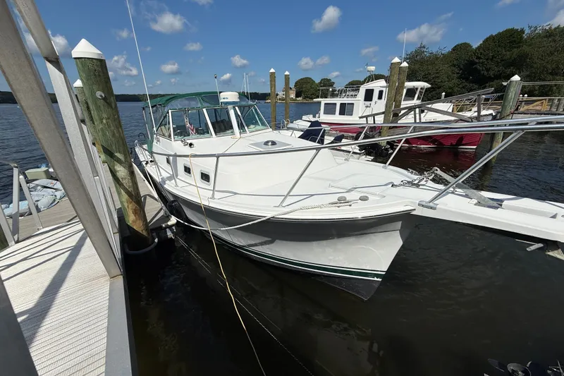 The Image of 2000 Mainship Pilot 30 docked at marina under clear blue sky. - 0