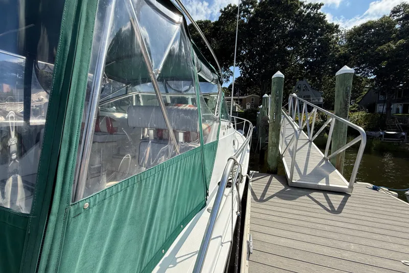 Slide: The Image of 2000 Mainship Pilot 30 docked, featuring green canopy and clear windows, with a wooden pier. - 8