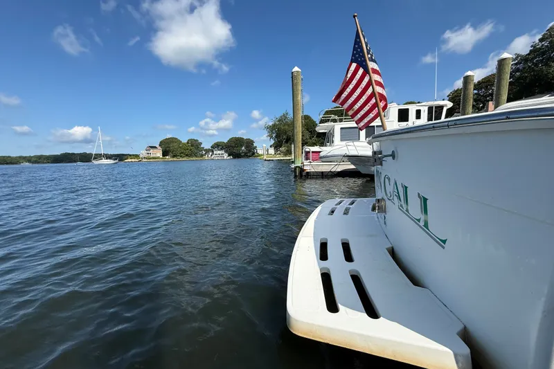 Slide: The Image of Mainship Pilot 30 boat docked, American flag waving, scenic waterfront view, blue sky, 2000 model. - 7