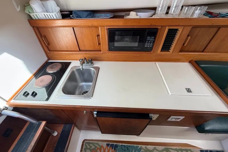 Slide: The Image of Compact kitchen area in a 2000 Mainship Pilot 30 boat with stove, sink, and microwave. - 23