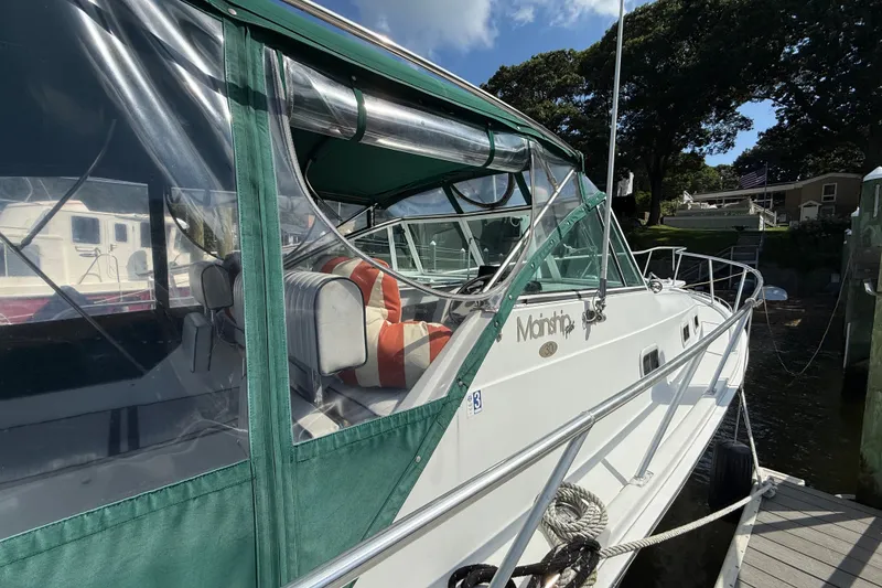 Slide: The Image of 2000 Mainship Pilot 30 boat docked, featuring green canopy and striped seating. - 10