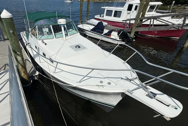 Slide: The Image of A 2000 Mainship Pilot 30 docked, featuring a green canopy and sleek white design. - 1