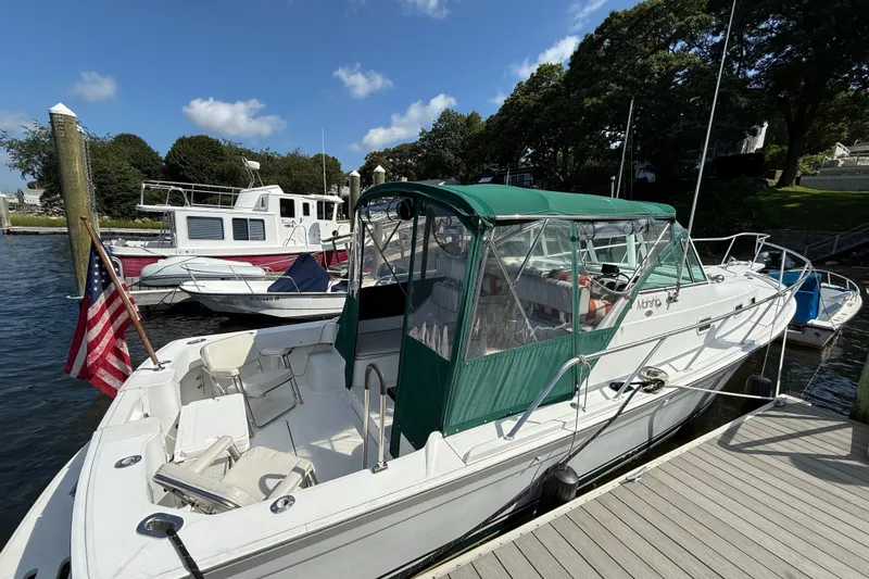 Slide: The Image of 2000 Mainship Pilot 30 docked, featuring green canopy and American flag, under clear skies. - 11