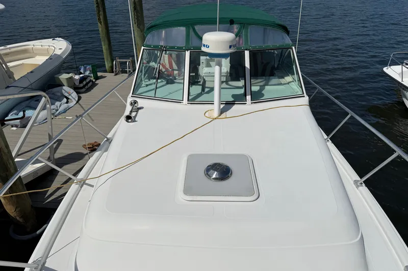 Slide: The Image of 2000 Mainship Pilot 30 boat docked, featuring a green canopy and white deck. - 2