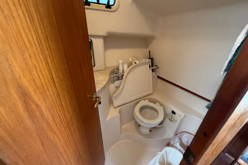 Slide: The Image of Compact bathroom in a 2000 Mainship Pilot 30 boat, featuring a toilet and sink. - 27