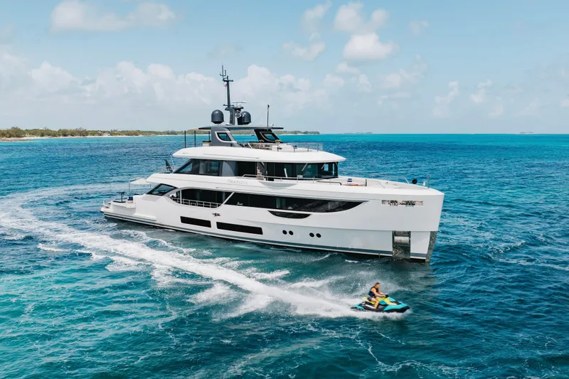 Slide: The Image of Luxury yacht Benetti Oasis 34 cruising in turquoise waters, 2023 model, with jet ski nearby. - 0