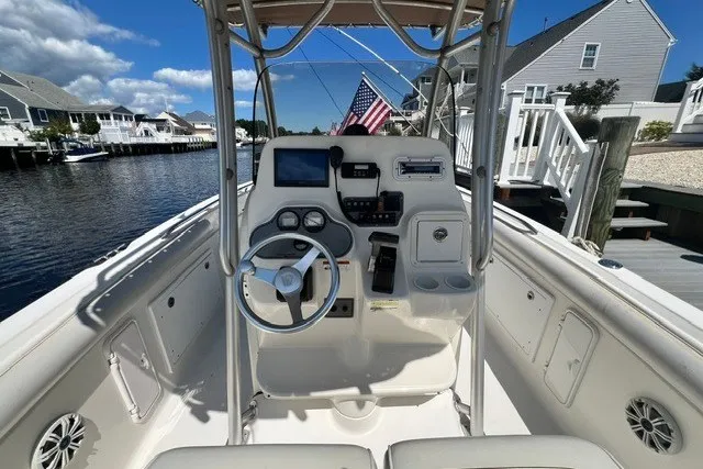 Slide: The Image of 2004 Wellcraft 252 Fisherman boat cockpit with steering wheel, control panel, and American flag. - 2