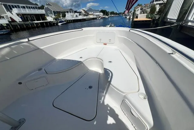 Slide: The Image of 2004 Wellcraft 252 Fisherman boat interior, spacious deck with storage compartments, docked by waterfront homes. - 9