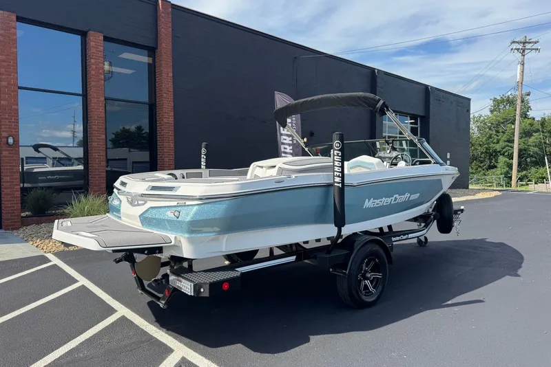 Slide: The Image of 2023 MasterCraft ProStar boat on trailer outside a modern building. - 1