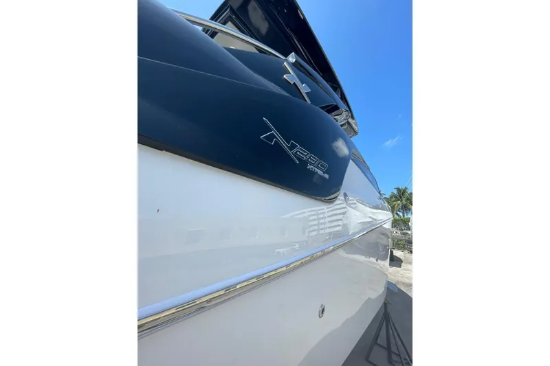 Slide: The Image of 2024 NX Boats NX280 XTREME side view with logo, under clear blue sky. - 4