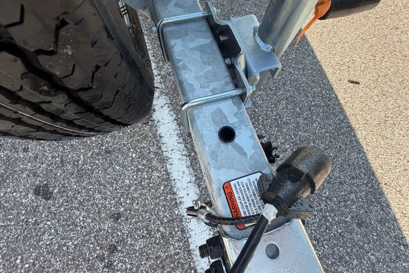 Slide: The Image of Trailer hitch and tire of a 2027 Mako Pro Skiff 17 CC on asphalt. - 11