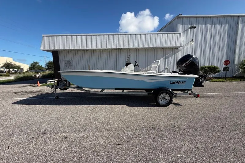 Slide: The Image of 2027 Mako Pro Skiff 17 CC boat on trailer, parked outside a building. - 1