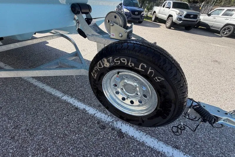 Slide: The Image of Trailer wheel of a 2027 Mako Pro Skiff 17 CC boat in a parking lot. - 10