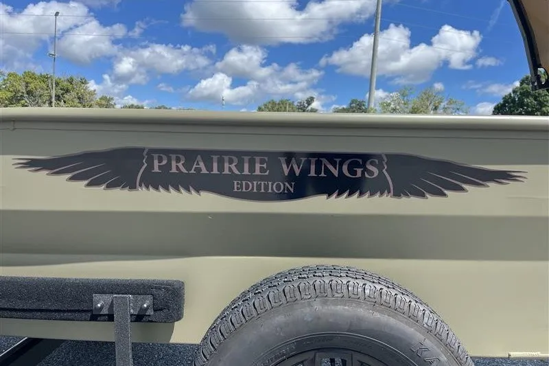 Slide: The Image of 2027 Tracker Grizzly 1650 T Prairie Wings Edition with logo and tire detail under blue sky. - 43