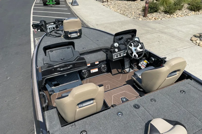 Slide: The Image of 2027 Nitro Z19 XL boat interior with steering wheel and seating, parked on pavement. - 13