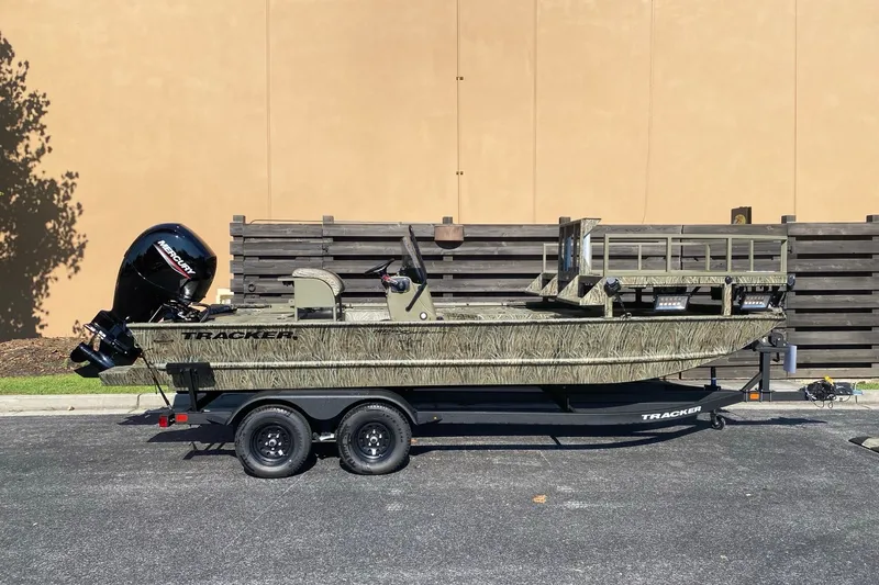 The Image of 2027 Tracker Grizzly 2072 CC Sportsman boat on trailer, camo design, parked outdoors. - 0