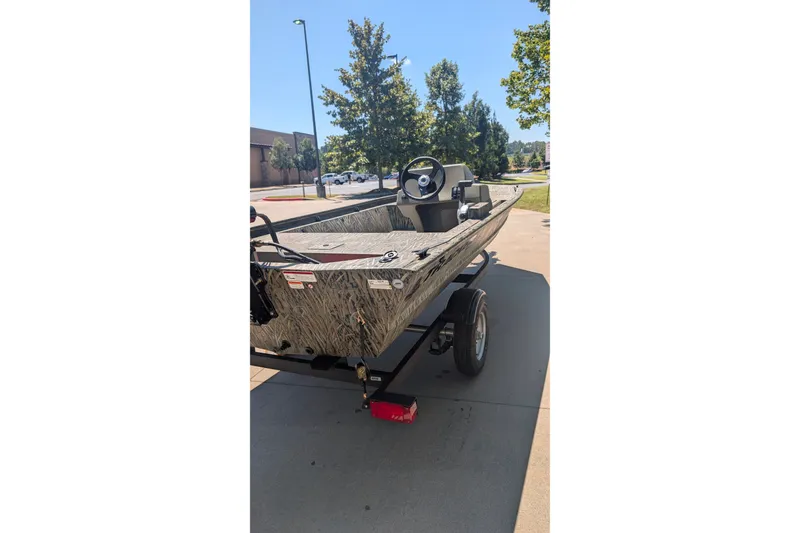 Slide: The Image of 2027 Tracker Grizzly 1648 SC boat on trailer, parked outdoors on a sunny day. - 16