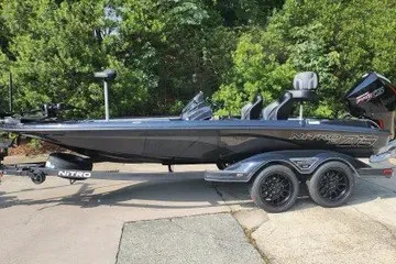 The Image of 2027 Nitro Z19 XL boat on trailer, parked outdoors with lush greenery background. - 0