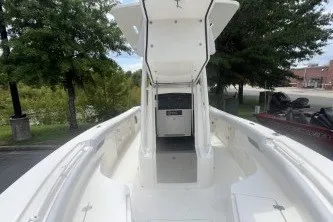 Slide: The Image of 2027 Mako 226 Center Console boat with open deck and console, surrounded by trees. - 1