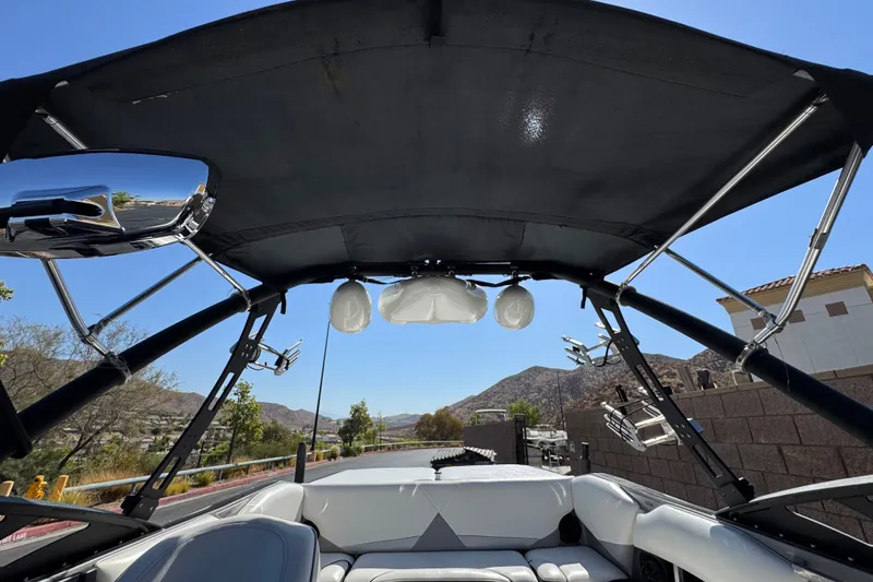 Slide: The Image of 2011 Axis A22 boat interior with wakeboard tower, speakers, and rearview mirror under clear blue sky. - 15