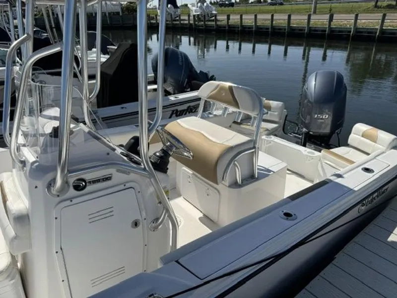 Slide: The Image of A 2023 Edgewater 188CC boat docked in a calm marina. It features beige and white upholstery. - 8