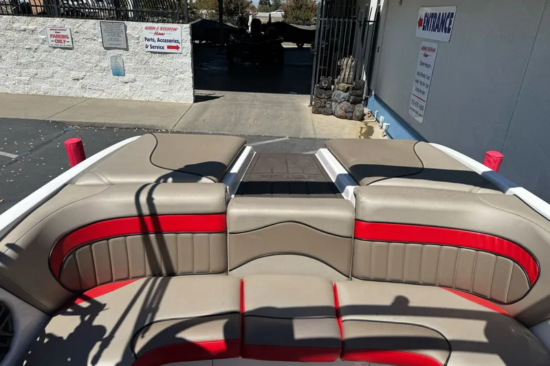 Slide: The Image of 2019 Sanger 212 SL boat interior with beige and red seating at a service entrance. - 14