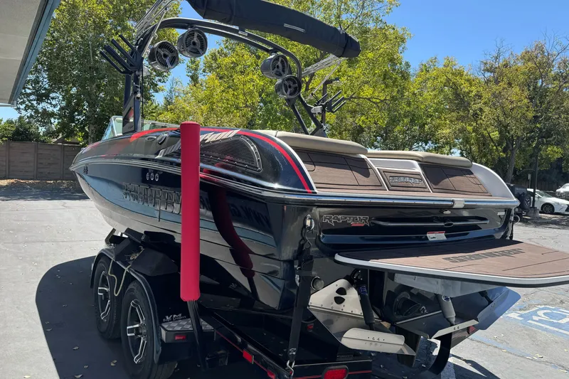 Slide: The Image of 2019 Sanger 212 SL boat on trailer, parked outdoors, with trees in background. - 5