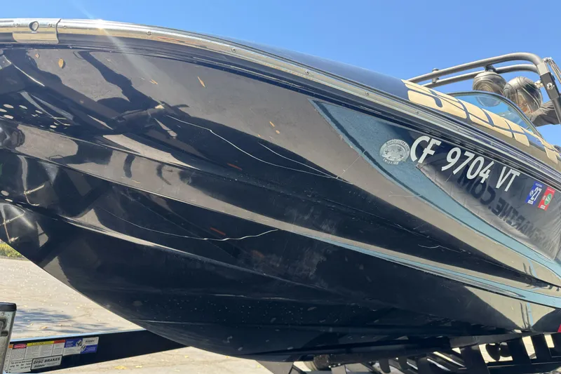 Slide: The Image of 2019 Sanger 212 SL boat with visible hull scratches on a trailer. - 1