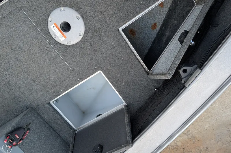 Slide: The Image of 2012 Lund 1875 Pro-V IFS boat interior with storage compartments and carpeted flooring. - 12