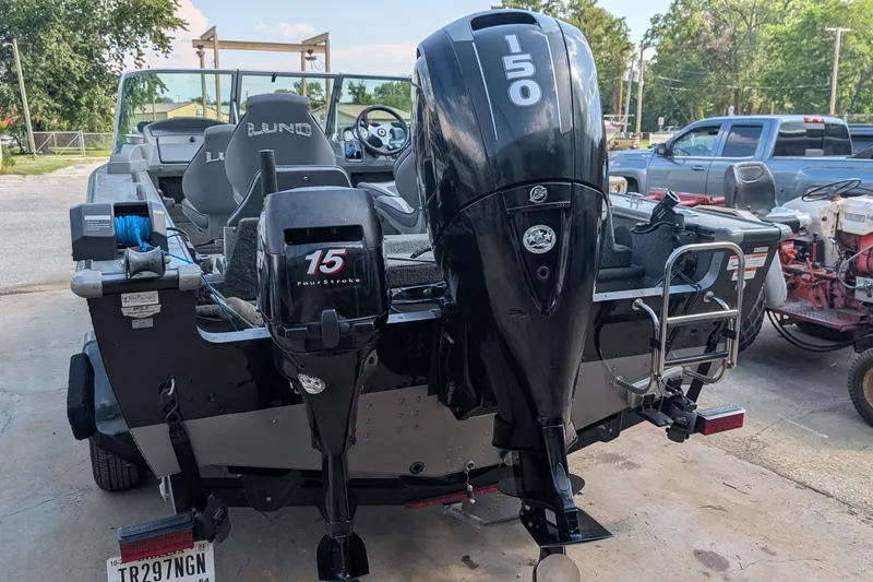 Slide: The Image of 2012 Lund 1875 Pro-V IFS boat with dual outboard motors, parked outdoors. - 2