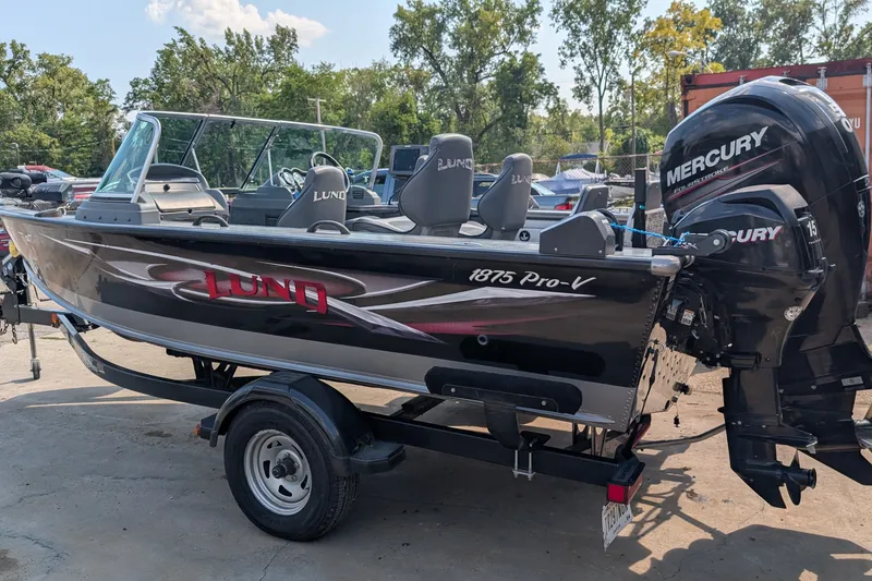 Slide: The Image of 2012 Lund 1875 Pro-V IFS boat with Mercury engine, parked outdoors. - 1