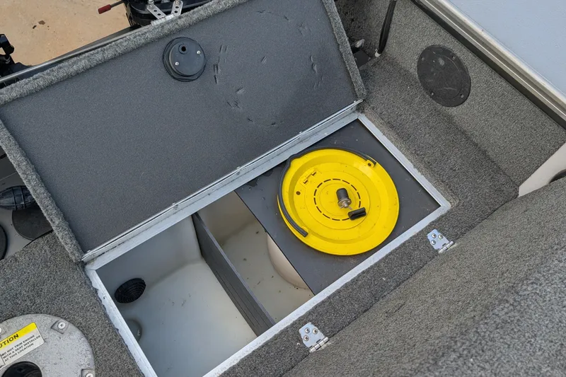 Slide: The Image of 2012 Lund 1875 Pro-V IFS boat storage compartment with yellow lid and gray carpet interior. - 17
