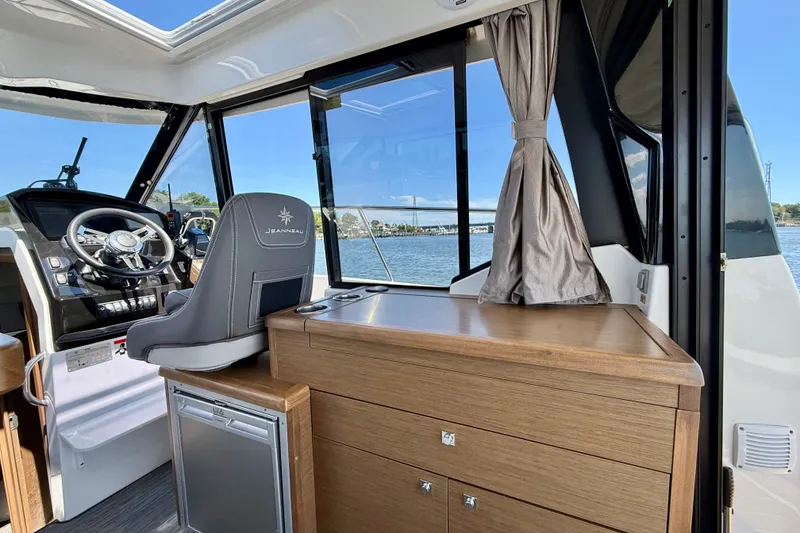 Slide: The Image of Interior of 2019 Jeanneau NC 895 boat with helm, wooden cabinetry, and water view. - 15