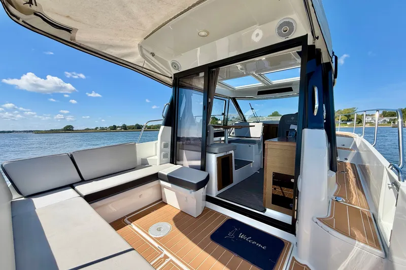 Slide: The Image of 2019 Jeanneau NC 895 boat interior with seating, open water view, and sunny weather. - 6